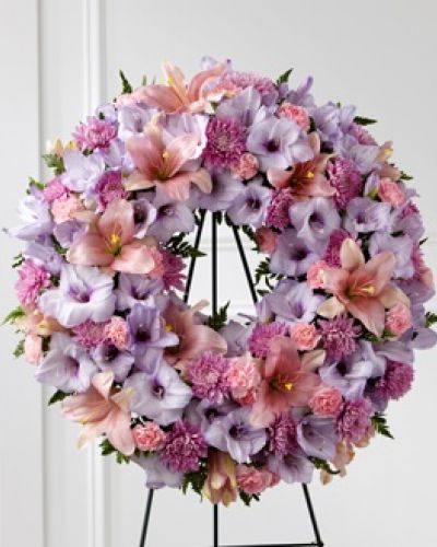 <p>Our Beloved Friend™ Wreath beautifully honors a life that was cherished by so many. This classic arrangement stands tall with an array of lilies, gladiolus and carnations in lavender and pink shades to express your love for the friends who truly feel like family.</p>